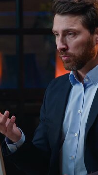 Serious concentrated Caucasian business man talking computer video call at night office focused middle-aged businessman male entrepreneur employer talk online conference communicate webcam at evening