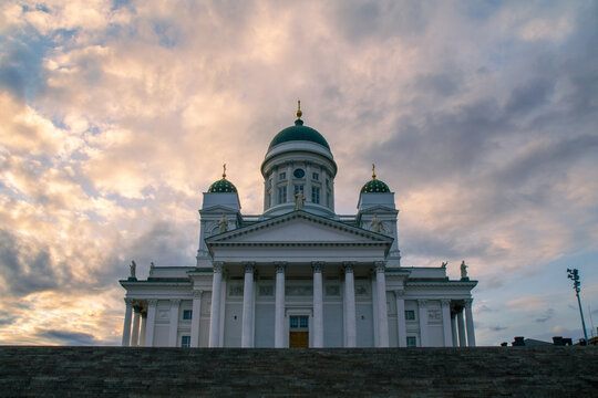 Neoclassical Helsinki cathedral with green domes against cloudy sky