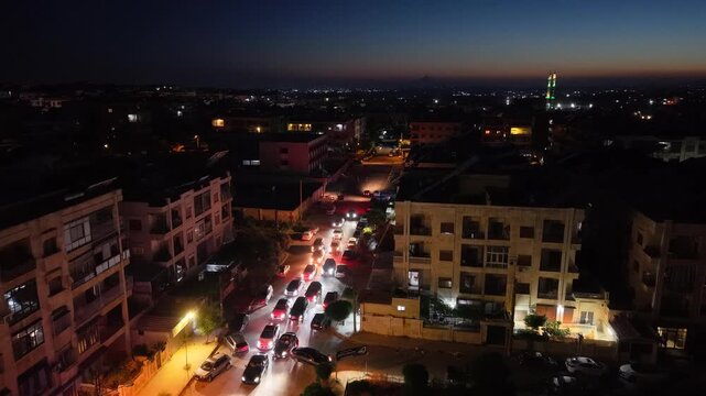 Aerial night view of an urban landscape in Syria featuring glowing city lights and illuminated streets.  Post-war Syrian cityscape and daily life at night.