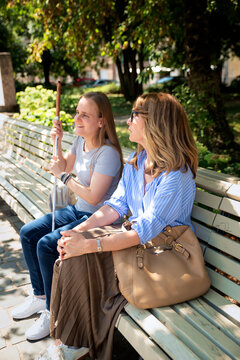 A woman with a disability and her female friend enjoying a summer day in a city park