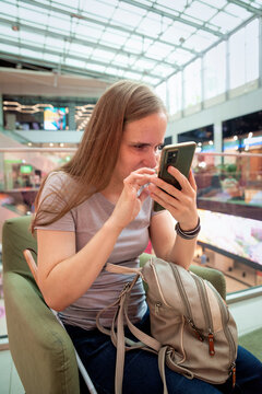 Visually impaired woman with white cane using smartphone app in shopping mall