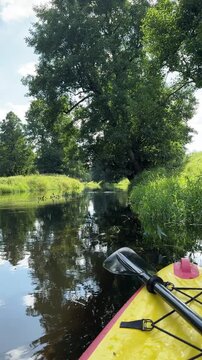 Yellow bow of kayak boat on a river in summer day. Rubber kayak on the water. Rafting, swimming, relaxing and resting on the river, a countryside getaway