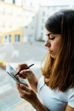 A woman uses a stylus pen on a tablet indoors in a hotel