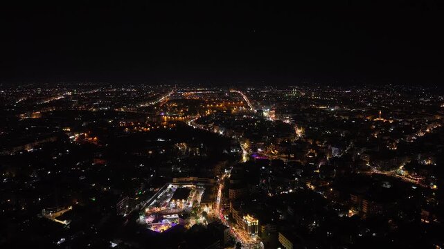 Aerial night view of an urban landscape in Syria featuring glowing city lights and illuminated streets.  Post-war Syrian cityscape and daily life at night.