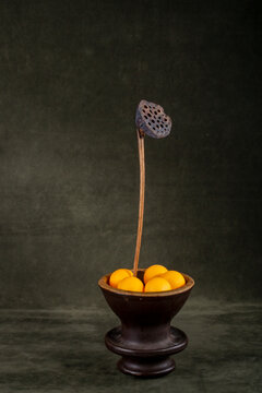 Dried lotus in a vase with marbles on a green background