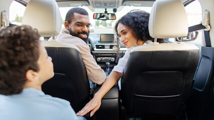 Obraz premium Happy African American family with son smiling inside car after school pickup