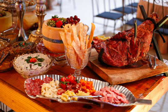 Buffet charcuterie and antipasto table featuring smoked ham on a wooden stand