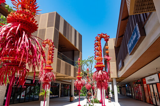 Sira village mall, Bali, Indonesia, August 16,2026: Traditional red Balinese penjor decorations frame modern outlet mall architecture under a vibrant clear blue sky.