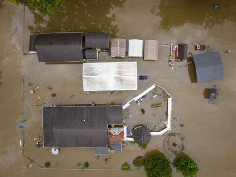 Aerial view of flooded residential properties in Broad Ripple surrounded by murky floodwaters with visible rooftops and debris in Indianapolis, Indiana, United States.