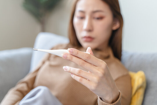 Woman measuring temperature her body on the bed. person got fever lying on the bed
