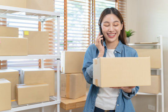 Young Asian woman owner of small online store packing customer orders in the home office.