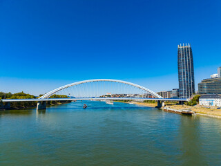 Naklejka premium View of the modern bridge over the river with buildings along the shore under a clear blue sky