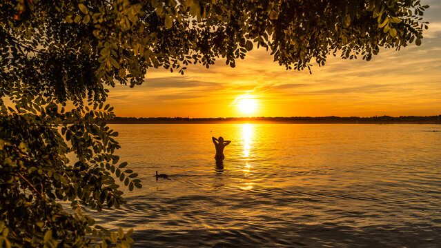Silhouette eine jungen Frau im Cospudener See bei Leipzig an einem wundersch&ouml;nen Sonnenuntergang