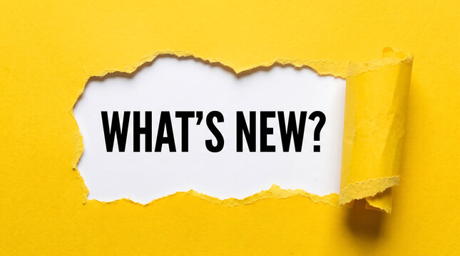 Whats new text message inside a torn yellow paper hole showing important business update news concept