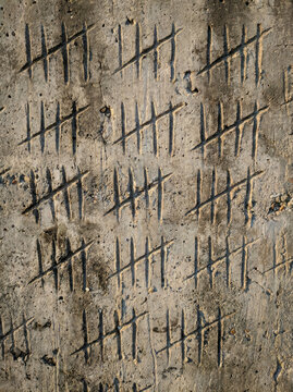 Tally marks on concrete wall create unique pattern, showcasing blend of art and texture