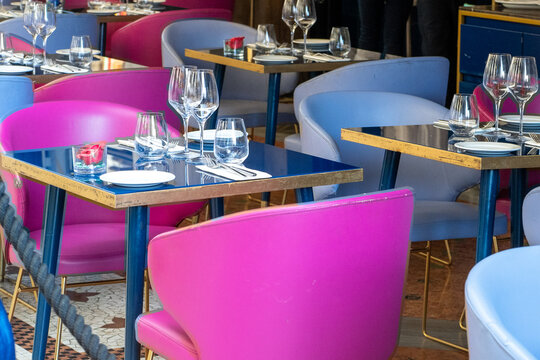 Elegant Restaurant Interior with Modern Pink and Blue Chairs, Glassware, and Set Tables for Fine Dining.