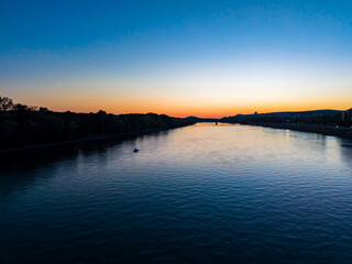 Fototapeta premium River during sunset seen from a bridge with clear skies and some land along the banks in a quiet location