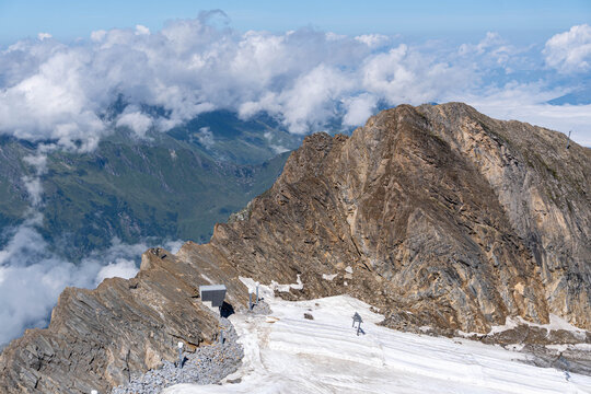 rugged alpine mountain peak rising above a snow covered glacier with dramatic clouds in the background