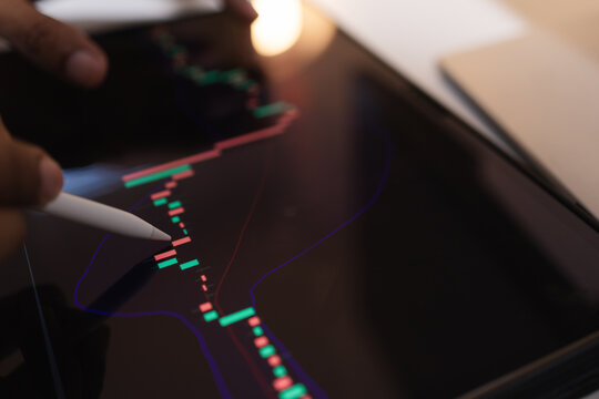 Professional trader analyzing stock market charts on laptop, tablet, and monitor while reviewing candlestick patterns, technical indicators, and market trends to support informed investment decisions.