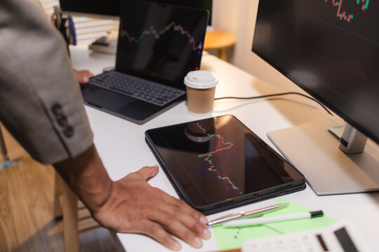 Professional trader analyzing stock market charts on laptop, tablet, and monitor while reviewing candlestick patterns, technical indicators, and market trends to support informed investment decisions.