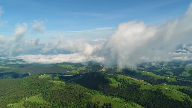Aerial Drone View of Lush Green Mountains and Rolling Hills with Drifting Clouds on a Clear Summer Day