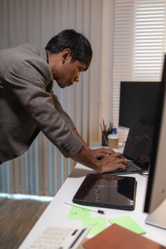 Professional financial analyst reviewing stock market charts across multiple screens using a tablet, laptop and calculator to evaluate price movements, technical indicators, and investment strategies.
