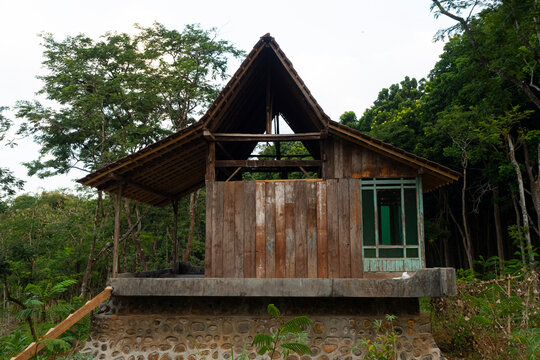 A traditional wooden forest hut used as a temporary resting shelter for agricultural workers, surrounded by lush tropical vegetation.