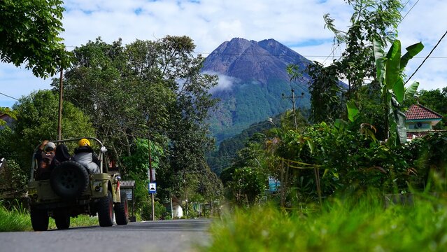 Off-road classic jeep driving on a scenic road towards the majestic Mount Merapi volcano