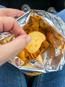 Hand reaching into foil chip bag for last potato chips