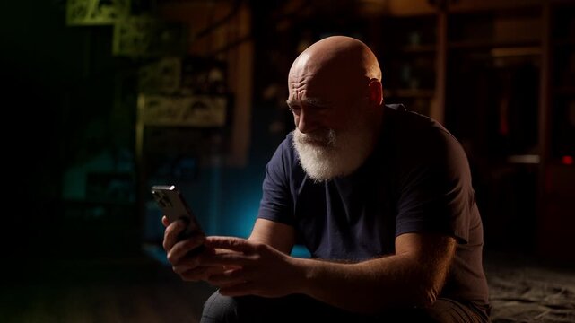 Crying middle-aged man looks at photo on phone, struggling with loneliness