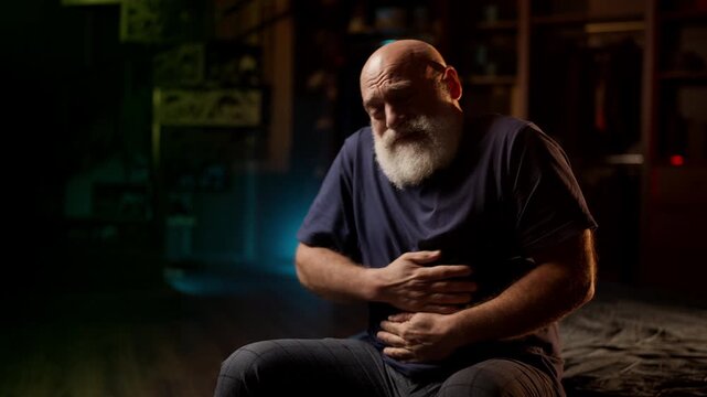 Upset middle-aged man experiences sharp abdominal pain at home, indigestion