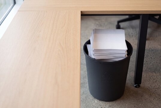 Paper recycling bin beneath a modern office desk