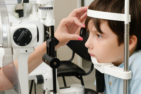 Young boy undergoing an eye examination with a slit lamp microscope in a modern ophthalmology clinic.