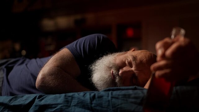 Drunk middle-aged man sleeps with liquor bottle, alcohol addiction concept