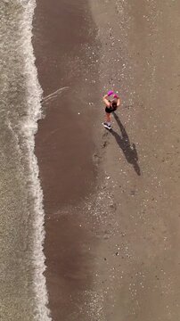 Aerial top view of a female fighter training kickboxing and punching on a sandy beach by the ocean