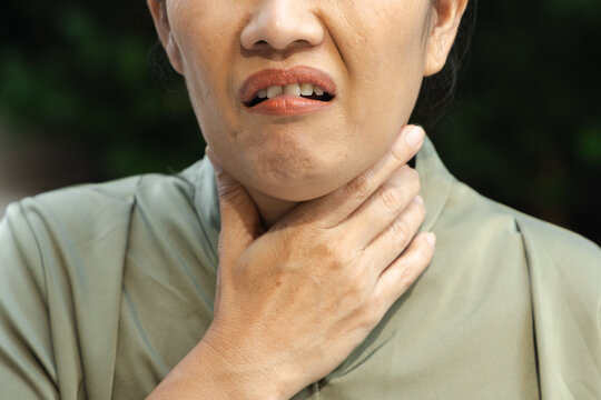 middle aged asian female suffering from cough and cold symptoms outdoors, weak and unwell, body parts closeup shot