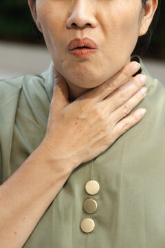 middle aged asian female suffering from cough and cold symptoms outdoors, weak and unwell, body parts closeup shot