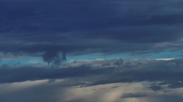 Time-lapse of dramatic storm clouds moving across a deep blue sky with patches of light breaking through