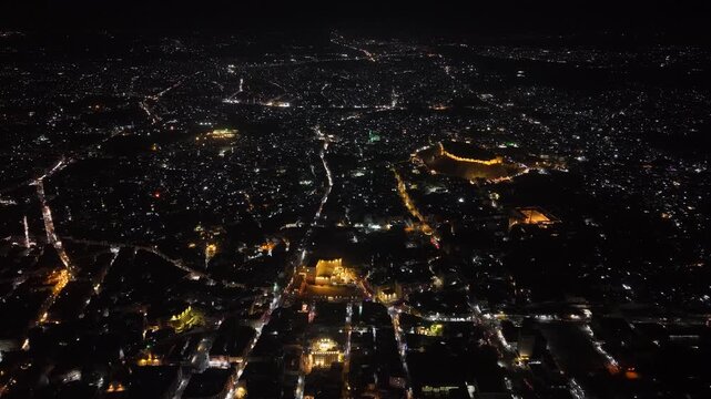Aerial night view of an urban landscape in Syria featuring glowing city lights and illuminated streets.  Post-war Syrian cityscape and daily life at night.