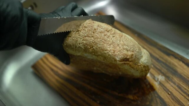 Someone trying to cut a thick sourdough bread. Sourdough is a type of bread leavened naturally using a fermented starte a mixture of flour and water rather than commercial yeast.