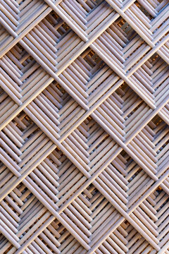 Close up texture of an intricate geometric cross-hatched woven rattan lattice pattern.