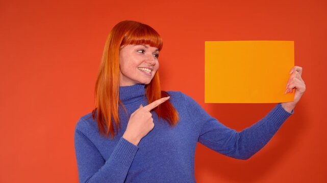 Cheerful person shows orange paper with bright smile in indoor location