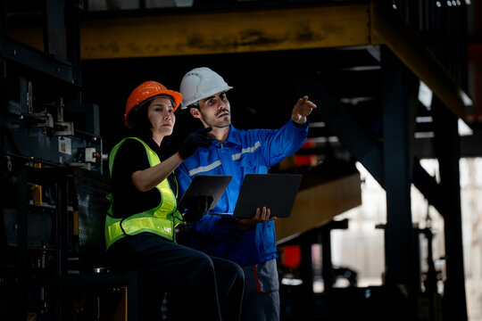 Industrial teamwork and production management. Engineers inspect manufacturing equipment and record production data inside a modern factory. Industry, teamwork, inspection, manufacturing, quality
