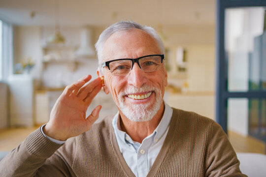 Headshot portrait of senior man with hearing aid, elderly male indoors with assistive listening device, hearing care, healthcare support and retirement lifestyle concept