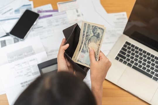 Close up of a person hands taking out banknotes, cash or money from a leather wallet while calculating home budget, planning expense and doing personal finance management.