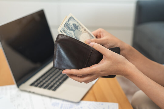 Close up of a person hands taking out banknotes, cash or money from a leather wallet while calculating home budget, planning expense and doing personal finance management.