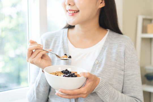 Healthy lifestyle, wellness food asian young woman hand use spoon eat tasty fresh organic yogurt, dairy product in bowl breakfast meal at home. Snack tasty on diet nutrition delicious natural yoghurt