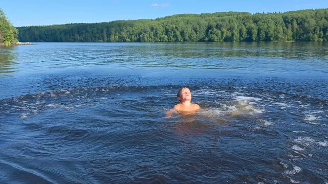 Boy diving off a bridge into the river doing a flip in summer, joyful holiday fun, playful childhood moment, active summer vacation.