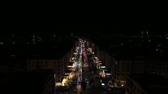 Aerial night view of an urban landscape in Syria featuring glowing city lights and illuminated streets.  Post-war Syrian cityscape and daily life at night.