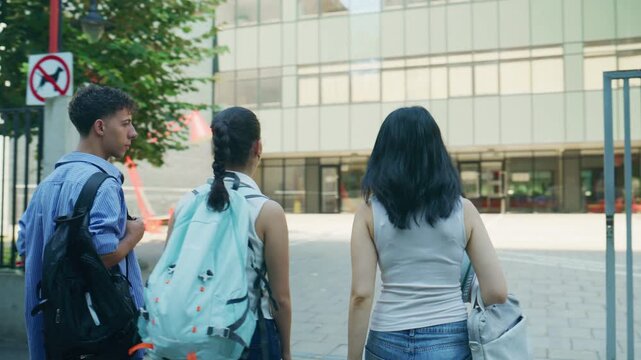 High school students greet friends with high-fives, heading into the school building. Young friends walk to campus, ready for a day of education and connection.
